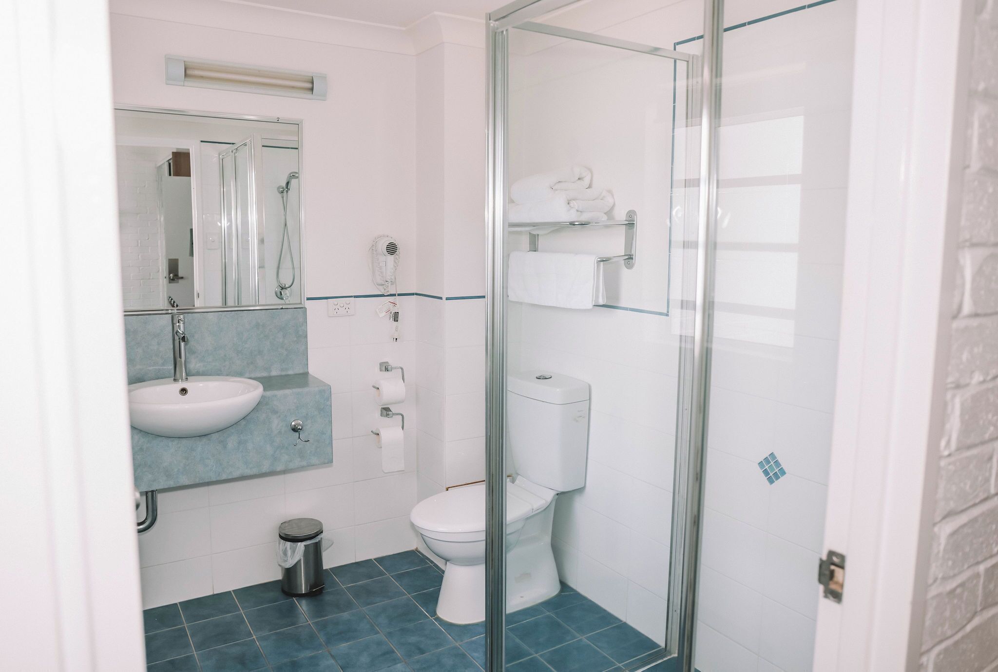 A bathroom with a glass shower enclosure, a white sink, and a toilet.