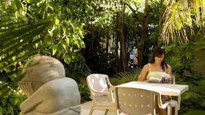 Una estatua en un jardín con una mesa y sillas.