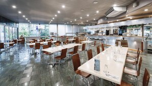 Un comedor interior amplio con varias mesas y sillas, una zona de cocina y una barra.