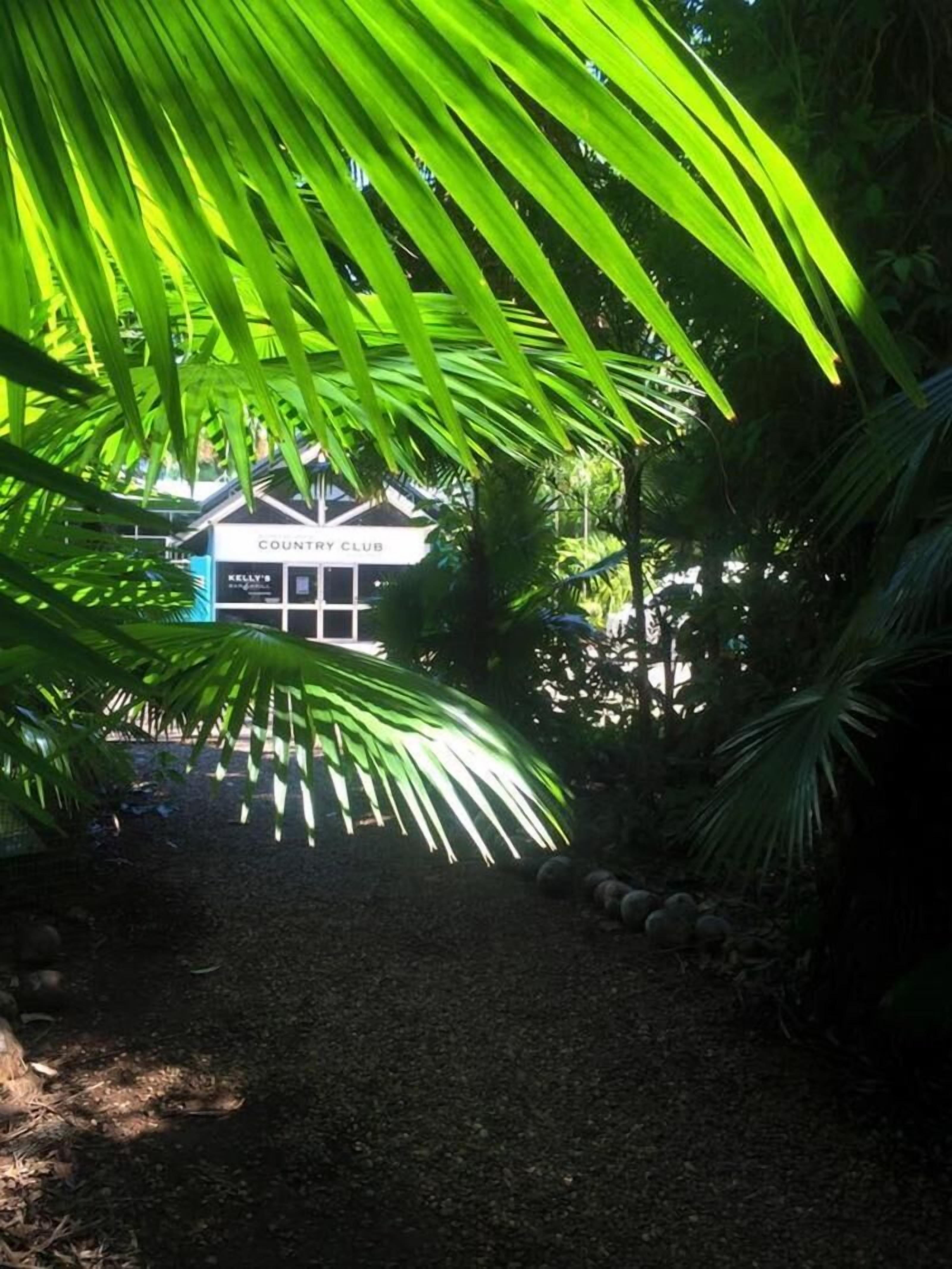 Un camino conduce a un edificio que dice 'COUNTRY CLUB', con un cartel que indica 'KELLY'S'.