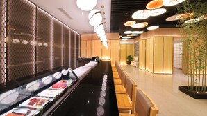 A modern interior with a long counter, seating area, and decorative lighting. - Central Hotel Jingmin (Xiamen)