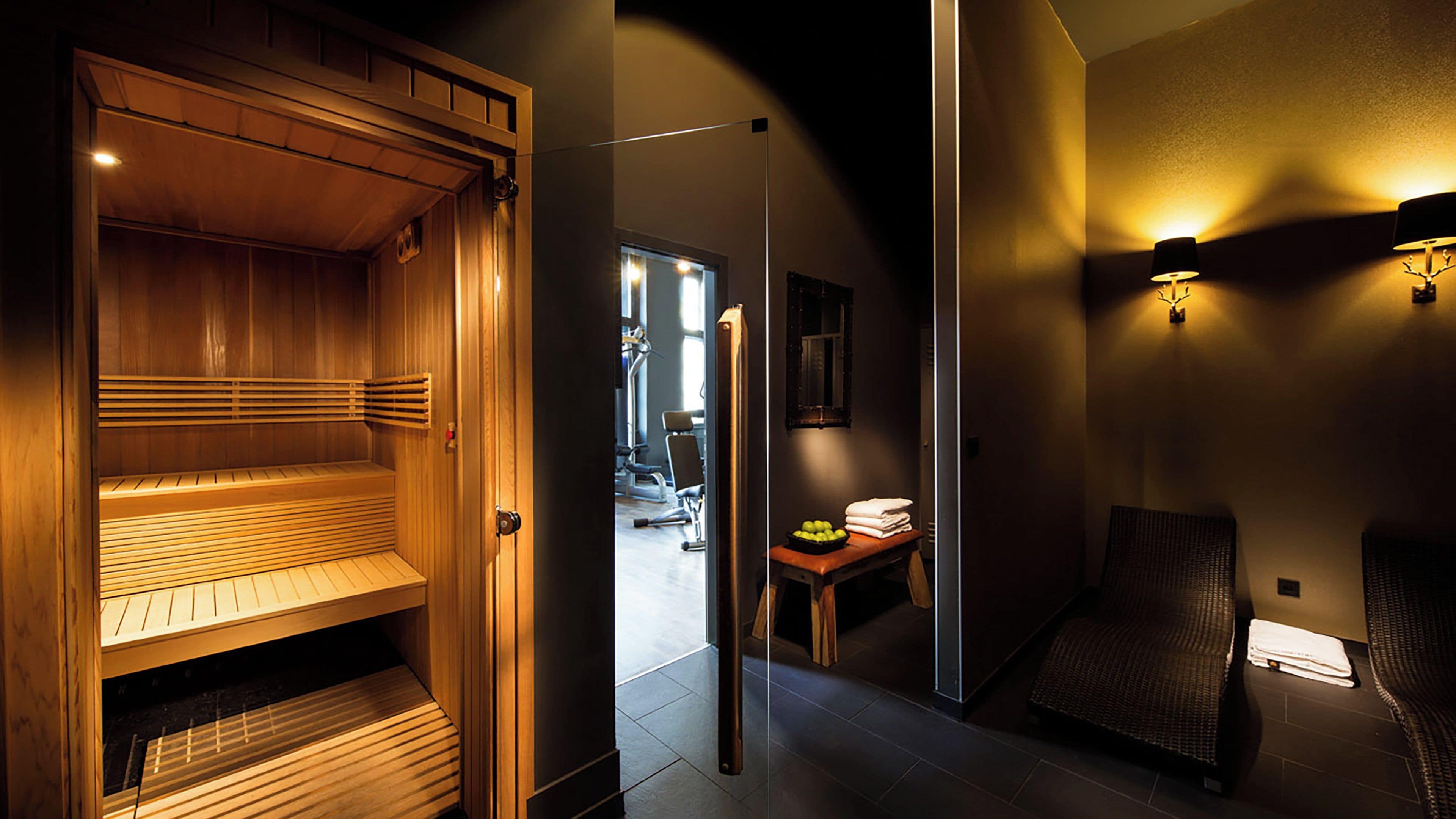 Un sauna con bancos de madera y una puerta de vidrio que da a un área de gimnasio.