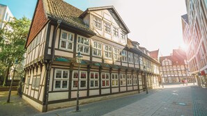 A traditional half-timbered building with multiple windows and a cobblestone street. - Pentahotel Braunschweig (Braunschweig)
