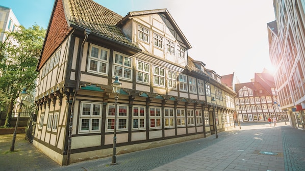 A traditional half-timbered building with multiple windows and a cobblestone street. - Pentahotel Braunschweig (Braunschweig)