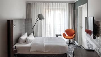 Habitación de hotel con cama, escritorio, silla, lámpara y un espejo grande.