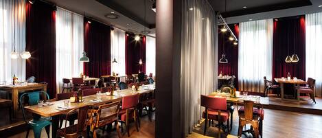A restaurant with multiple dining tables, chairs, and pendant lighting.
