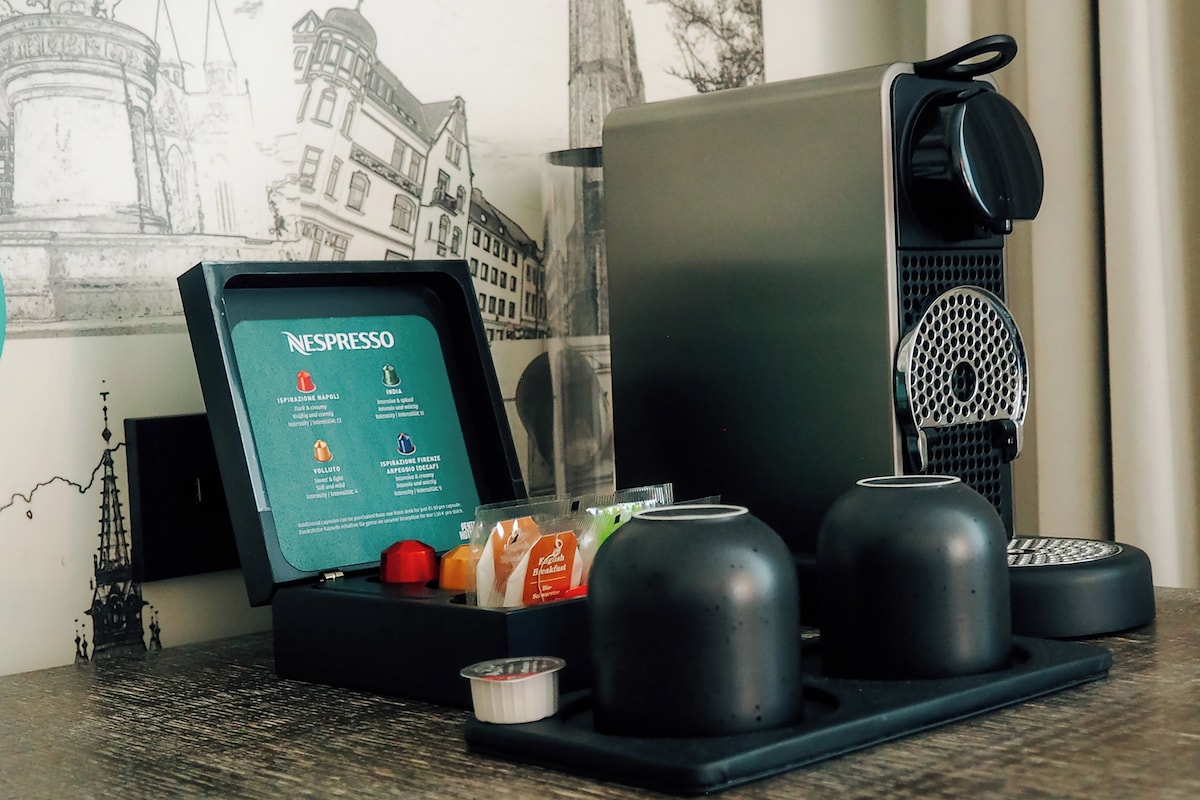 A Nespresso coffee machine with a menu, a cup, and a small bowl on a table.