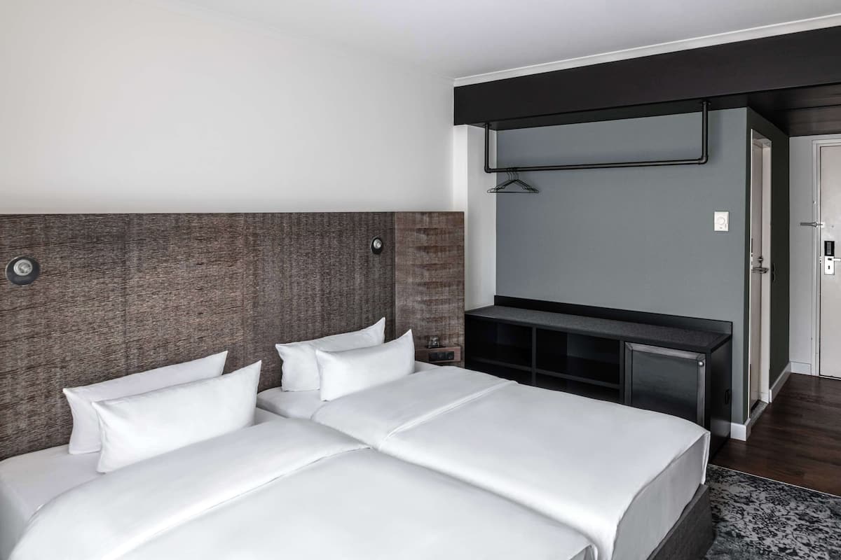 Una habitación de hotel moderna con una cama grande, un escritorio con una silla y un armario.