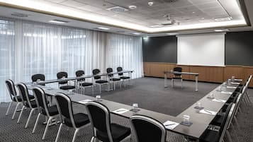 A conference room with a long table, chairs, a projector screen, and a whiteboard.