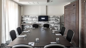 A conference room with a long table, six chairs, a TV screen, and a patterned wall. - pentahotel Braunschweig (Braunschweig)