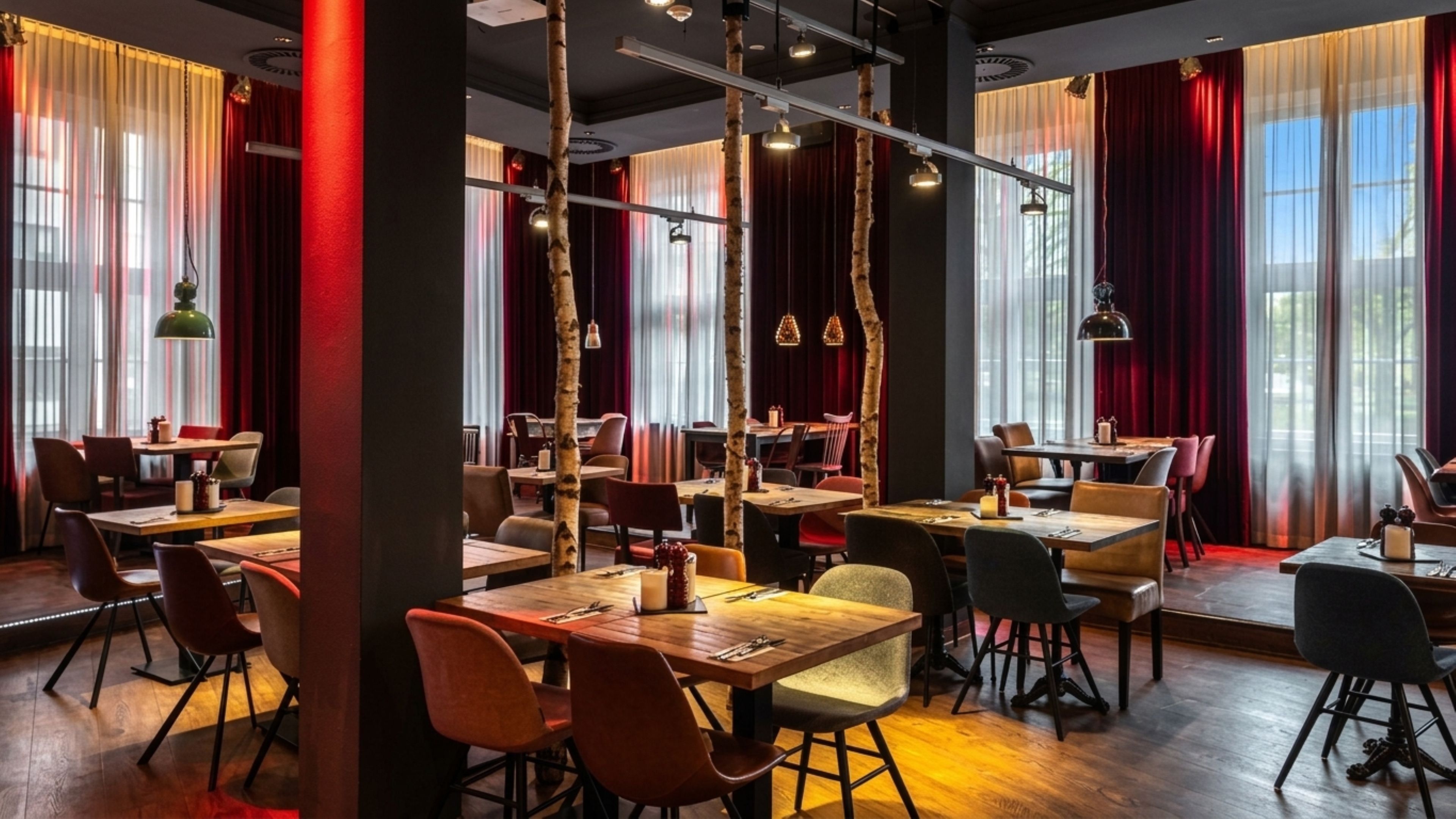 A restaurant interior with wooden tables, chairs, and hanging pendant lights.