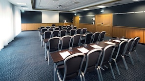 A conference room with a large table and chairs, a projector screen, and a door.