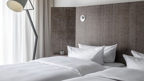 A hotel room with a large bed, a nightstand, a lamp, and a textured headboard. - Pentahotel Braunschweig (Braunschweig)