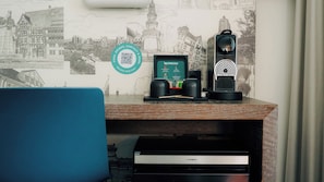 A desk with a Nespresso coffee machine, a smartphone, and a QR code for unlocking a stay. - Pentahotel Braunschweig (Braunschweig)