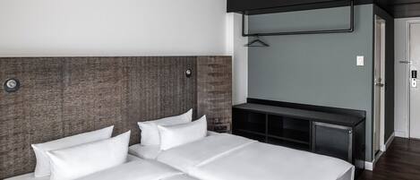 Una habitación de hotel con una cama grande, un escritorio pequeño, un televisor montado en la pared y una puerta que da a otra habitación.