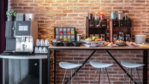 A coffee station with a coffee machine, cups, and a tray of fruits and snacks. - pentahotel Braunschweig (Braunschweig)