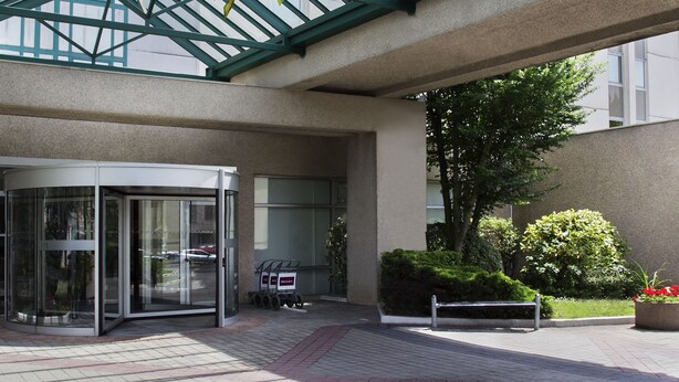 Un espace extérieur abrité, doté d’un toit en verre, d’une porte tournante et d’un chemin pavé.