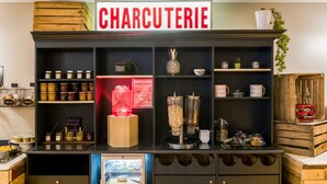 Un présentoir de charcuterie avec des pots de confitures, un moulin à café et une pancarte indiquant « CHARCUTERIE ».