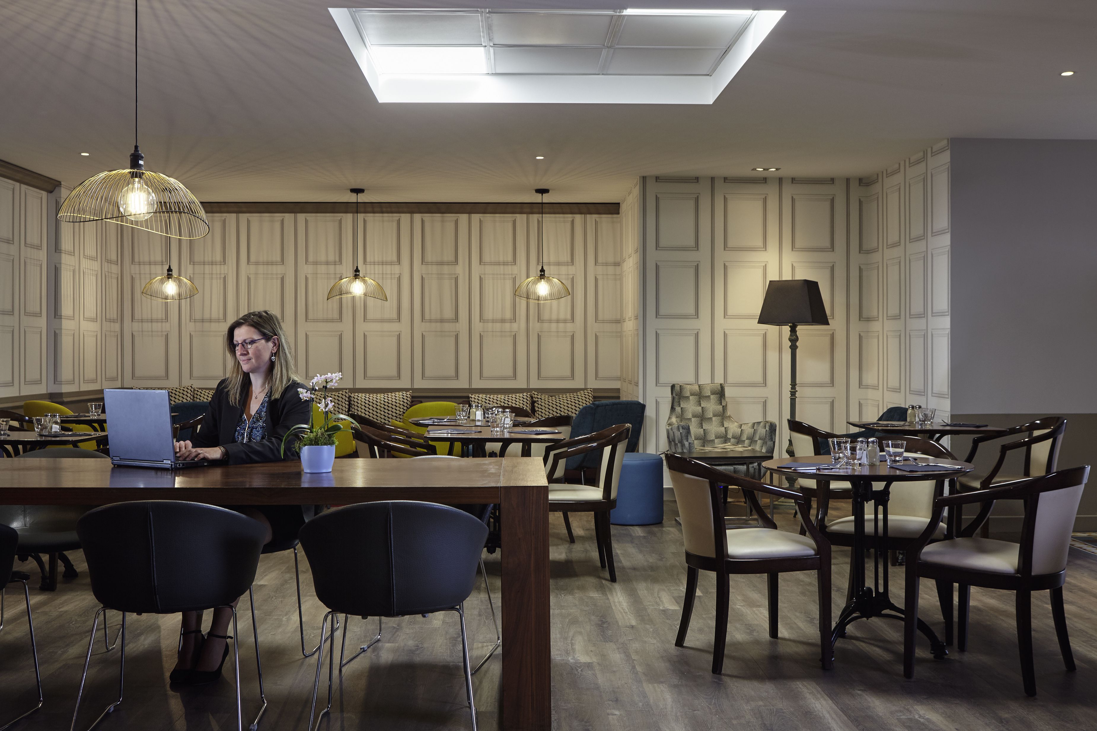 A modern dining area with a central table, multiple chairs, and pendant lighting.
