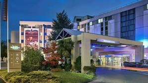 Une entrée d’hôtel moderne, avec une enseigne indiquant « Mercure Hotel », un jardin aménagé et un chemin dégagé menant à l’entrée.