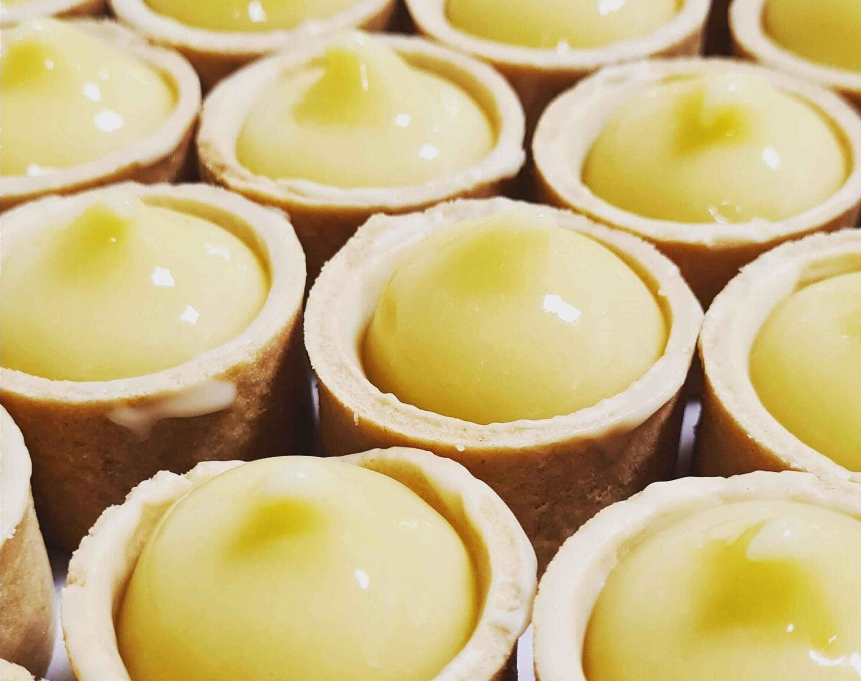 A close-up of multiple tart shells with a smooth, yellow filling.