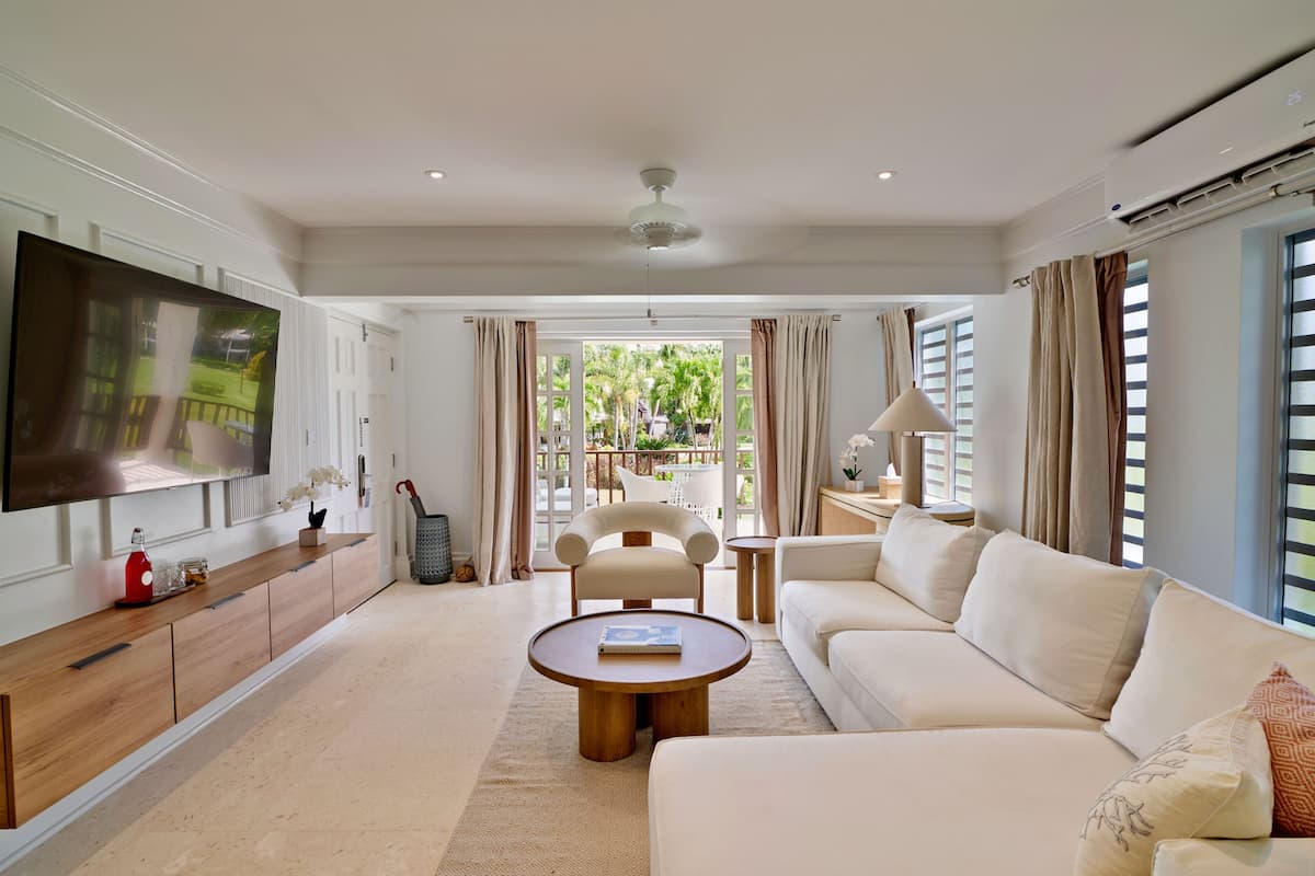 A modern living room with a flat-screen TV, a sofa, a coffee table, and a chair.