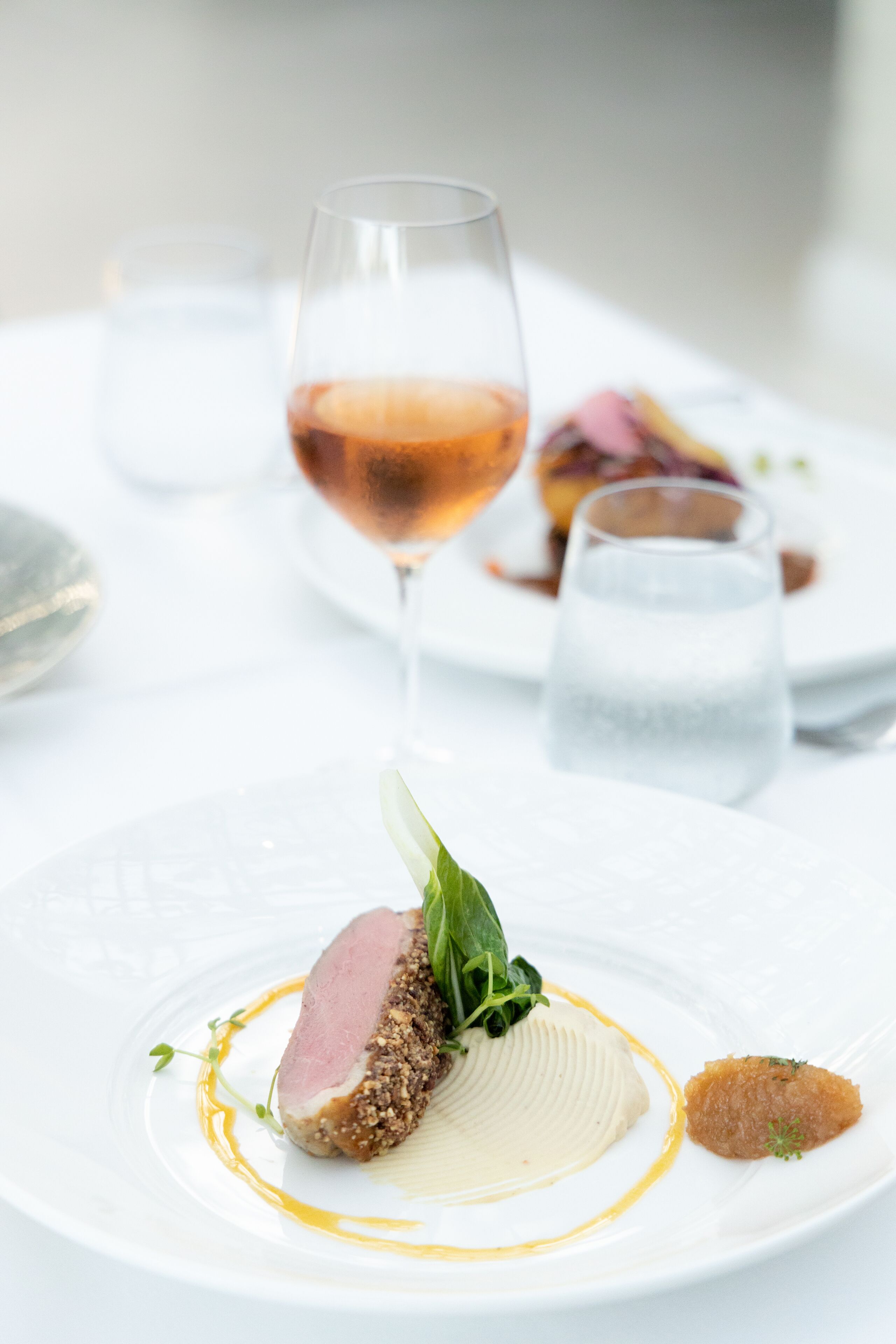 A white plate with a dish of food, a glass of wine, and a glass of water.