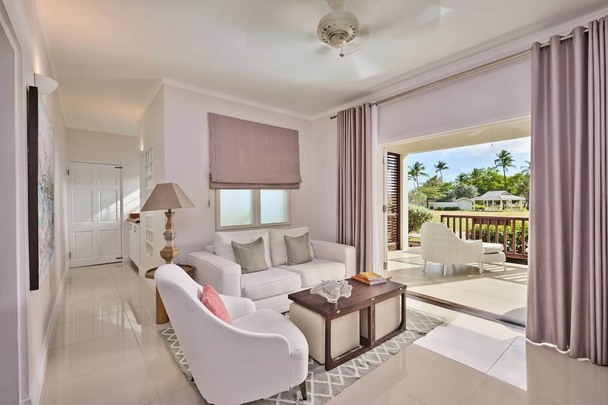 A spacious living room with a white sofa, a coffee table, and a view of the outdoors.