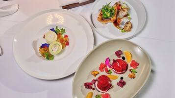 Three plates of food with various garnishes and a napkin with a utensil holder.