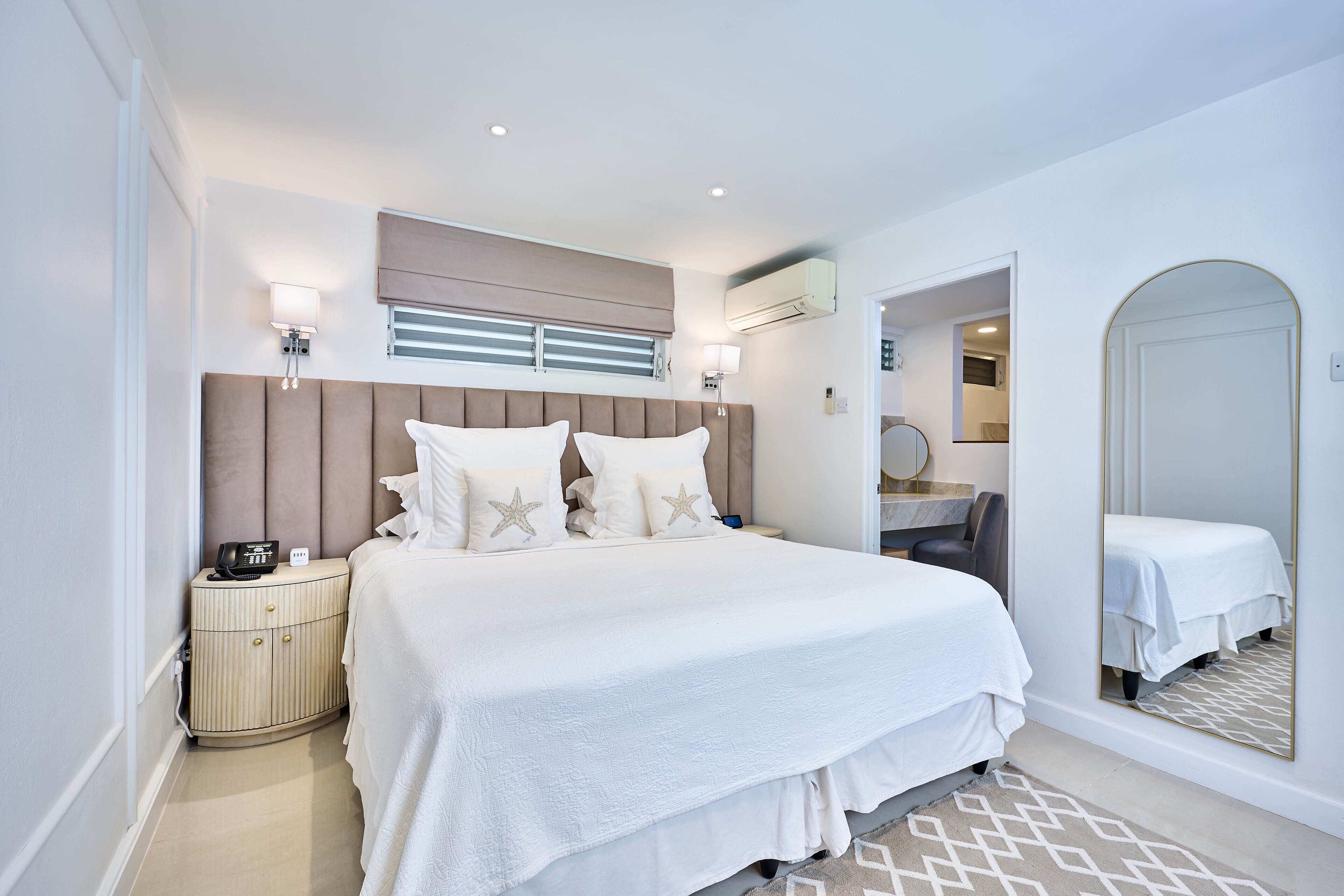 Una habitación de hotel moderna con una cama grande, mesitas de noche, un espejo y un armario.