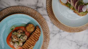A table with a blue plate of food, a woven placemat, and a marble surface.