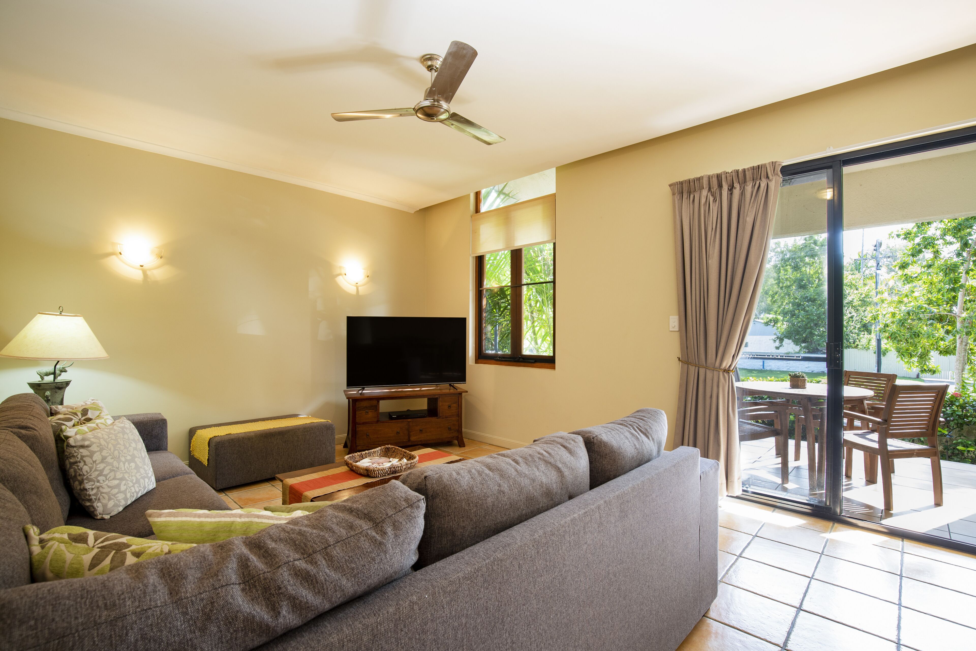A living room with a sofa, TV, and a ceiling fan.