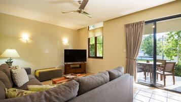 A living room with a sofa, TV, and a ceiling fan.