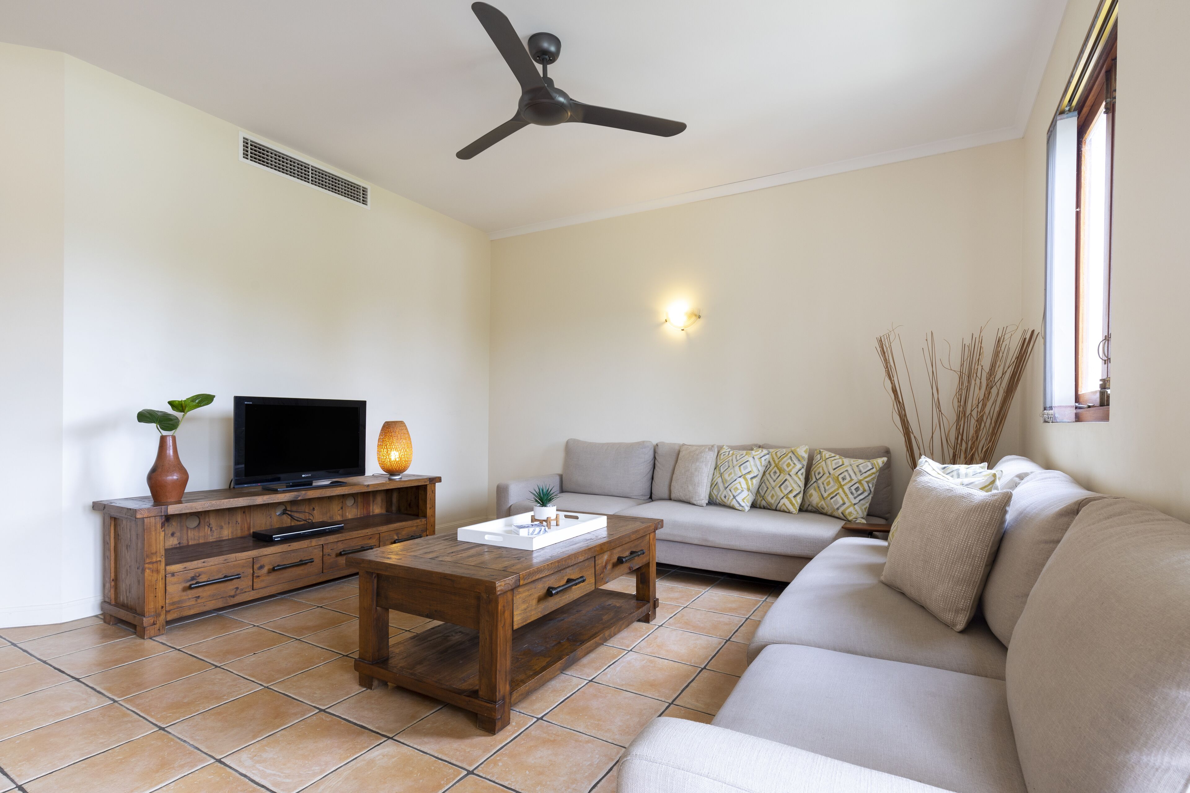Uma sala de estar com televisão, mesa de centro de madeira e um sofá.