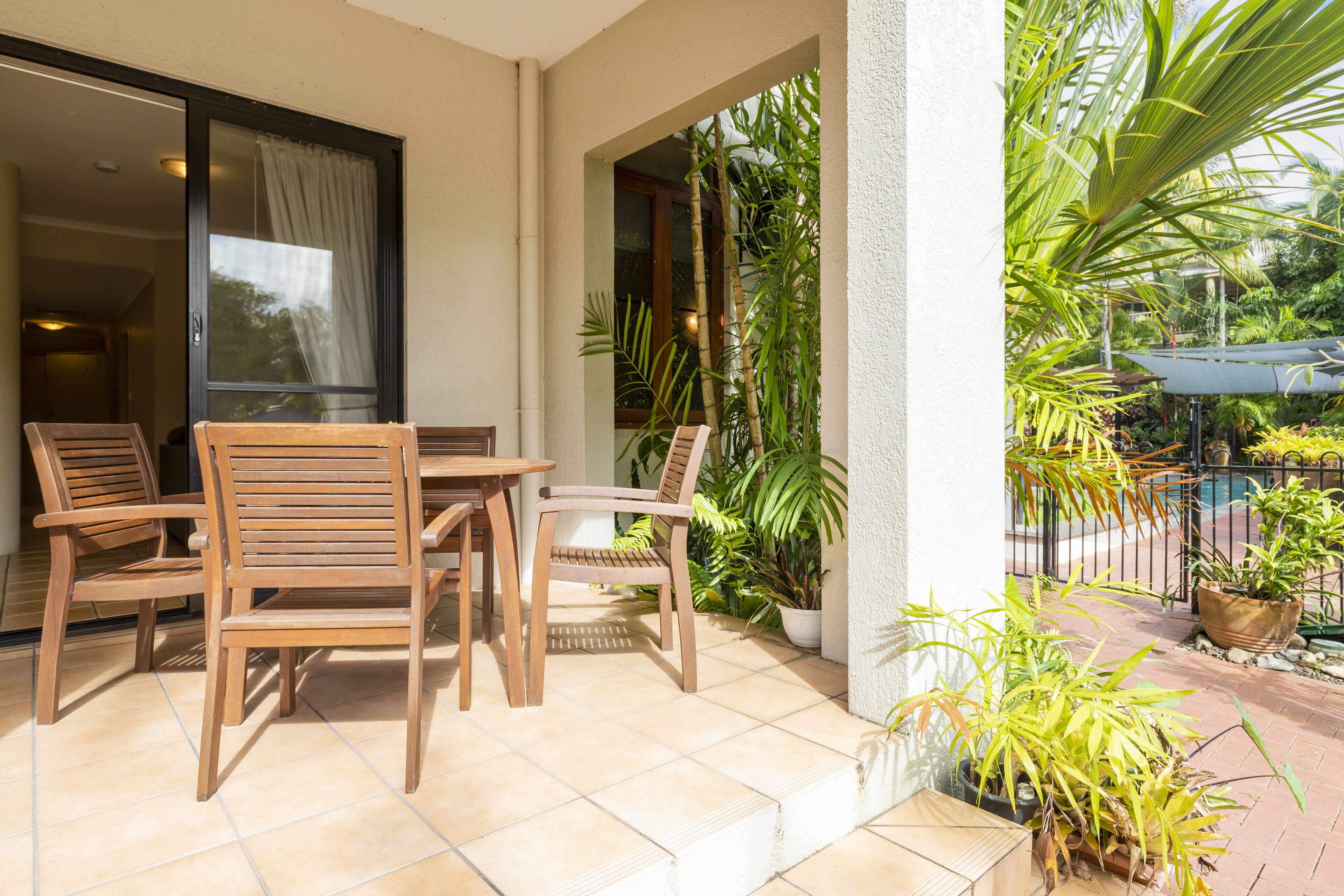 A patio with wooden furniture and potted plants.