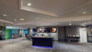 Un hall d’entrée spacieux avec un comptoir d’accueil, un mur végétal orné du logo « YM » et un mur décoré de tableaux encadrés.