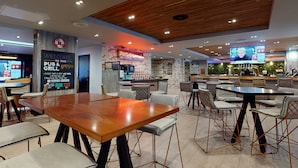 Un pub-restaurant moderne avec un plafond en bois, des murs en briques et plusieurs espaces de détente.