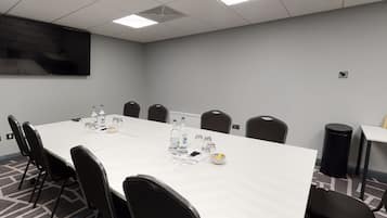 A conference room with a long table, chairs, a projector screen, and a whiteboard.