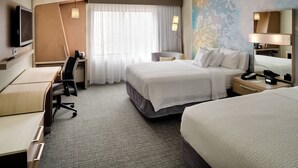 Habitación de hotel con cama, escritorio, silla, televisión y ventana con cortinas.