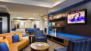 Un vestíbulo moderno de hotel con zona de estar, televisor de pantalla plana y bar.