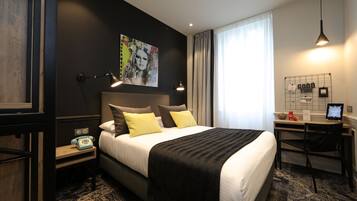 Una habitación de hotel moderna con una cama grande, un escritorio y una computadora.