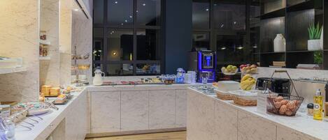 A modern kitchen with marble countertops, a wooden floor, and a view of the city at night.