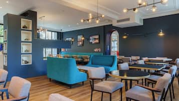 Un restaurant moderne aux murs bleus, au plancher en bois, et proposant différents types de sièges, notamment des tables et des canapés.