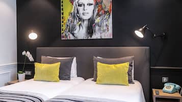 Un dormitorio moderno con una cama grande, dos lámparas de noche, un teléfono antiguo y un cuadro abstracto y llamativo en la pared.