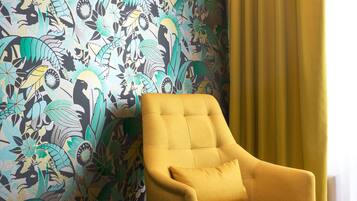 Une pièce avec un papier peint à motifs, un fauteuil jaune et un rideau jaune.