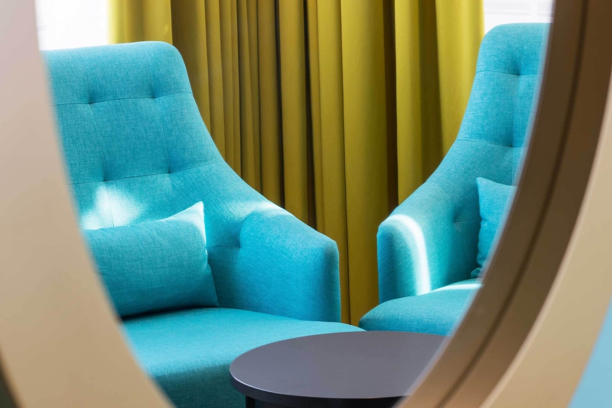 A room with two blue armchairs and a small round table.