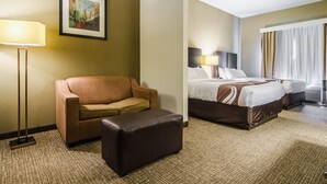 Ein Hotelzimmer mit einer Couch, einem Hocker und einem Bett mit zwei Kissen.
