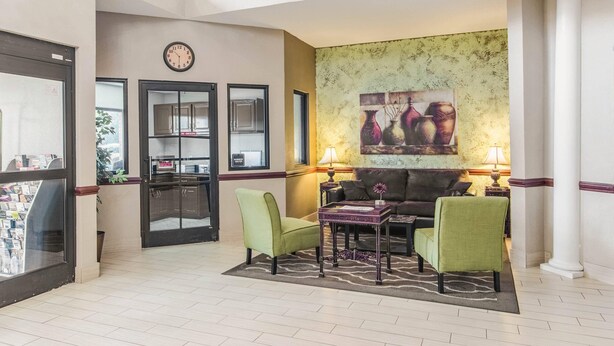 Eine Lobby mit einer Rezeption, einer Uhr, einer Sitzecke inklusive Sofa und Sesseln sowie einer Wand mit einer Vasenmalerei.