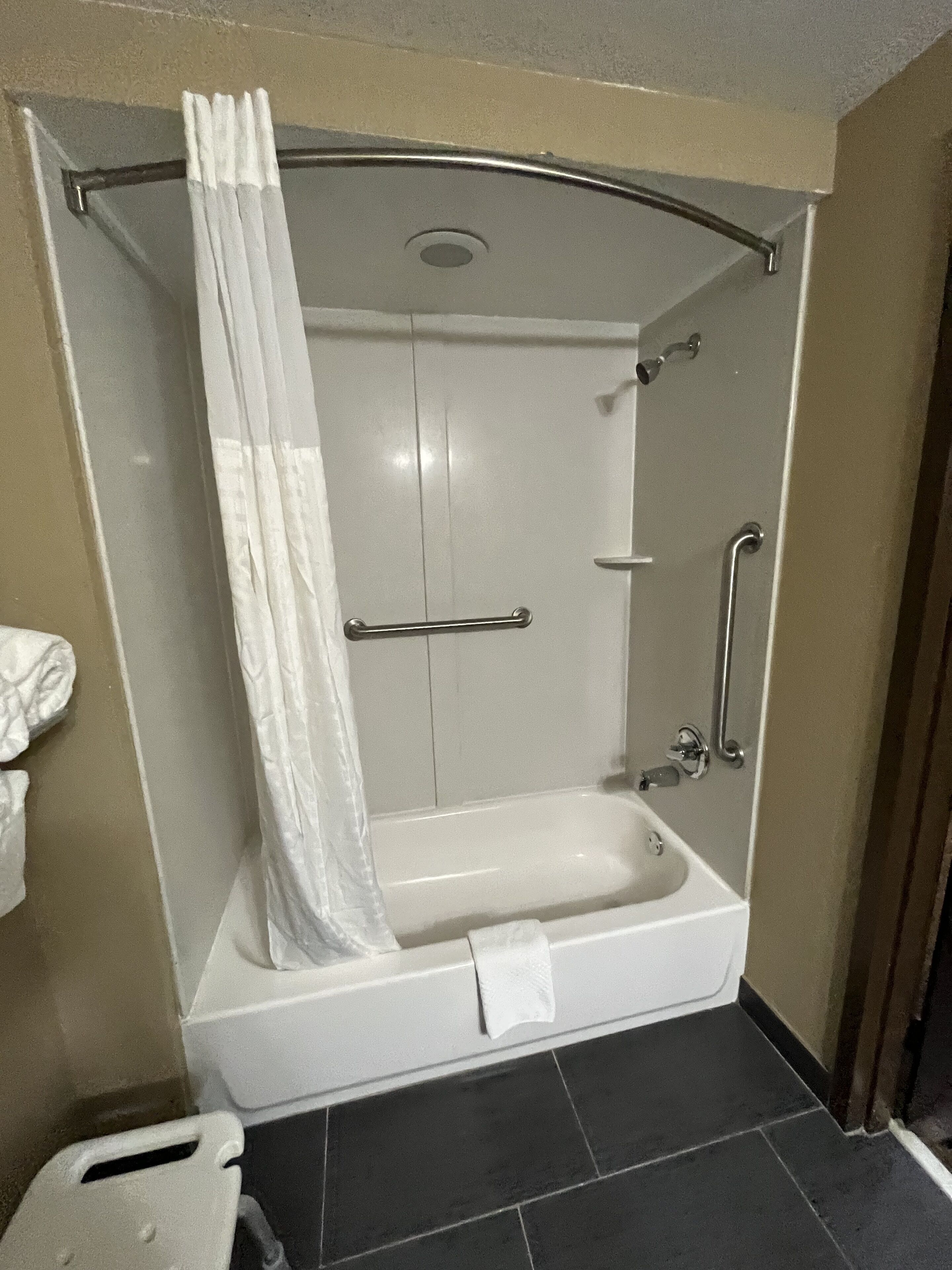 A walk-in shower with a glass door, a handheld showerhead, and a towel rack.