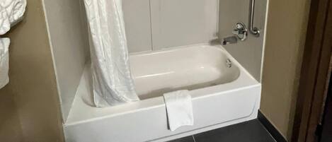 A white bathtub with a towel, a shower curtain, and a grab bar.